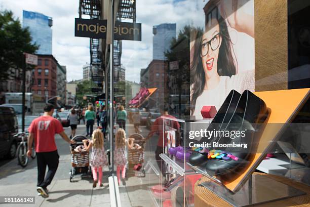 Family walks past shoes on display in the window of a Crocs Inc. Store in the shopping district of Soho in New York, U.S., on Saturday, Sept. 14,...