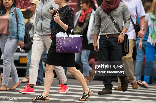 Shoppers walk with their shopping bags in the shopping district of Soho in New York, U.S., on Saturday, Sept. 14, 2013. Consumers views of the U.S....