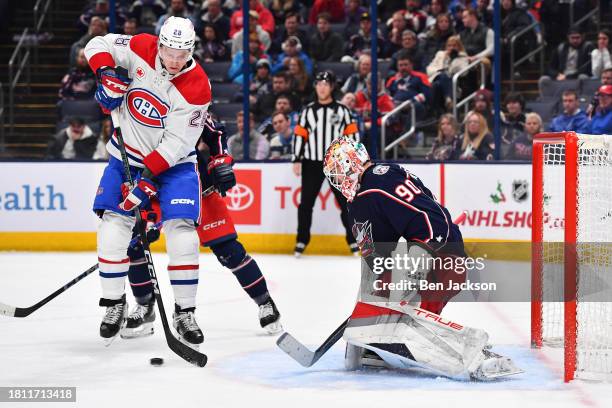 Goaltender Elvis Merzlikins of the Columbus Blue Jackets defends the net as Christian Dvorak of the Montreal Canadiens jumps to avoid the puck during...