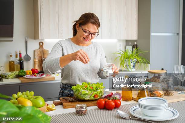 woman adding salt to a fresh healthy lettuce salad bowl - adding salt stock pictures, royalty-free photos & images