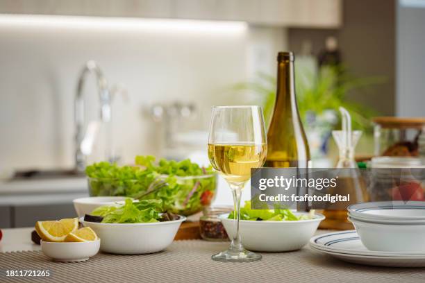 bicchiere da vino bianco e insalatiera sul tavolo della cucina - pinot grigio wine foto e immagini stock