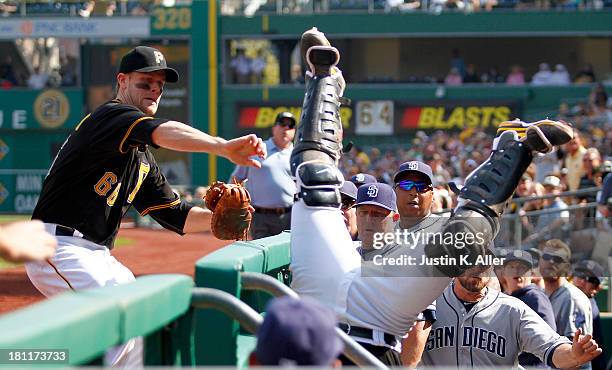 Justin Morneau of the Pittsburgh Pirates attempts to reach for Tony Sanchez of the Pittsburgh Pirates who tumbles over the railing after catching a...
