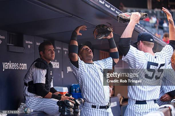 Robinson Cano of the New York Yankees stretches in the dugout with Lyle Overbay during the game against the New York Mets at Yankee Stadium on May...