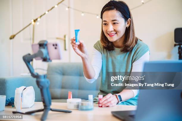 young beautiful asian female influencer doing a vlog post about organic skincare products at home - live broadcast stock pictures, royalty-free photos & images