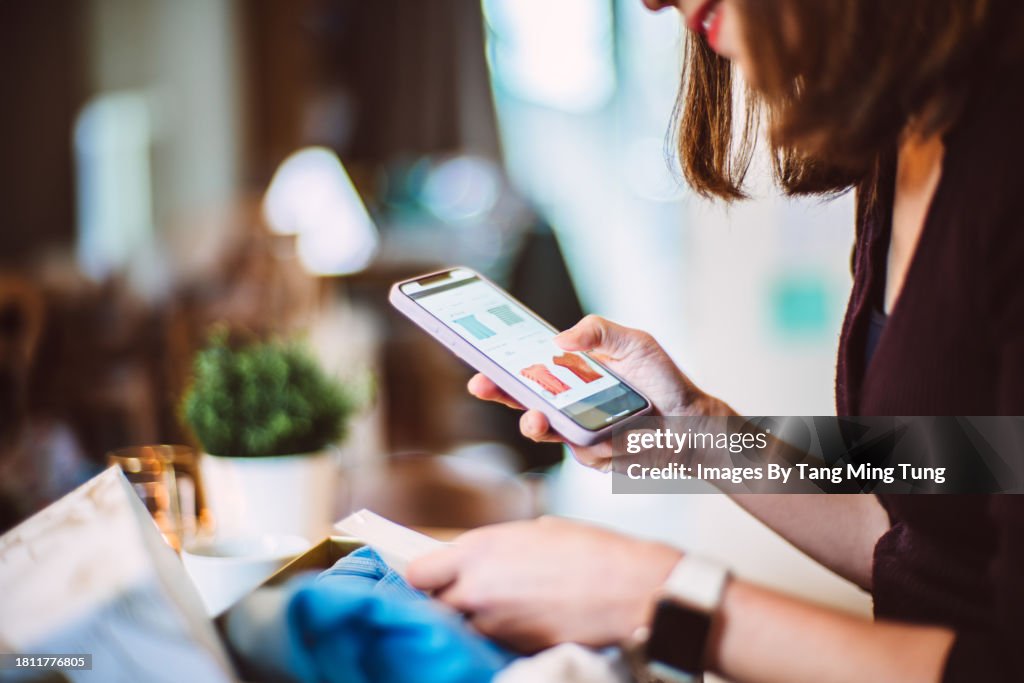 Young woman doing online shopping for clothes on smartphone at home