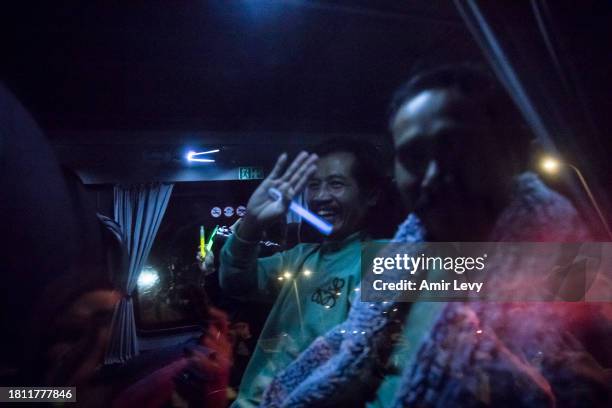 Released Thai hostages wave through a van window on November 30, 2023 in Ofakim, Israel. Israel and Hamas agreed to a two-day extension to their...