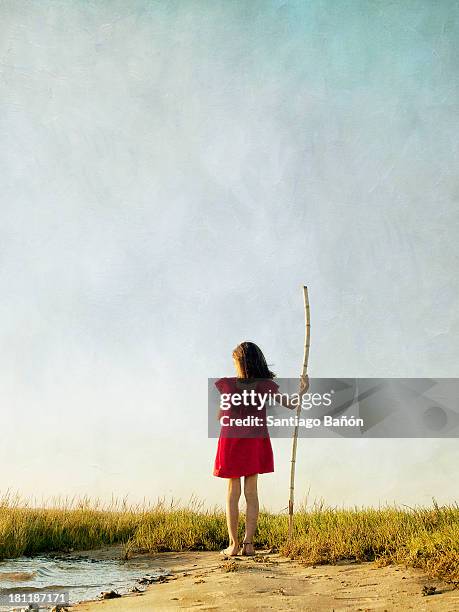 girl in red dress standing with wooden stick - kid stock stock-fotos und bilder