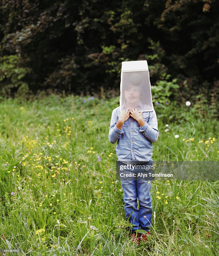 Young boy holding a box over his head outdoors