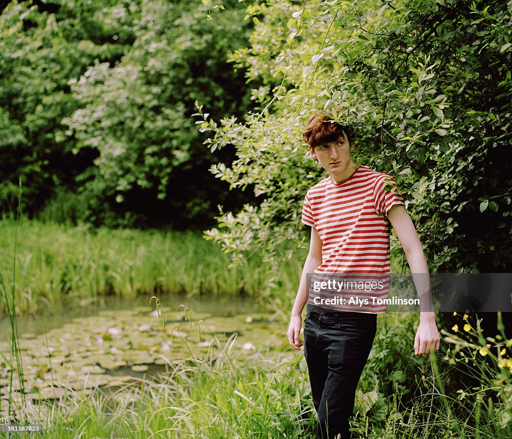 Boy standing next to a pond