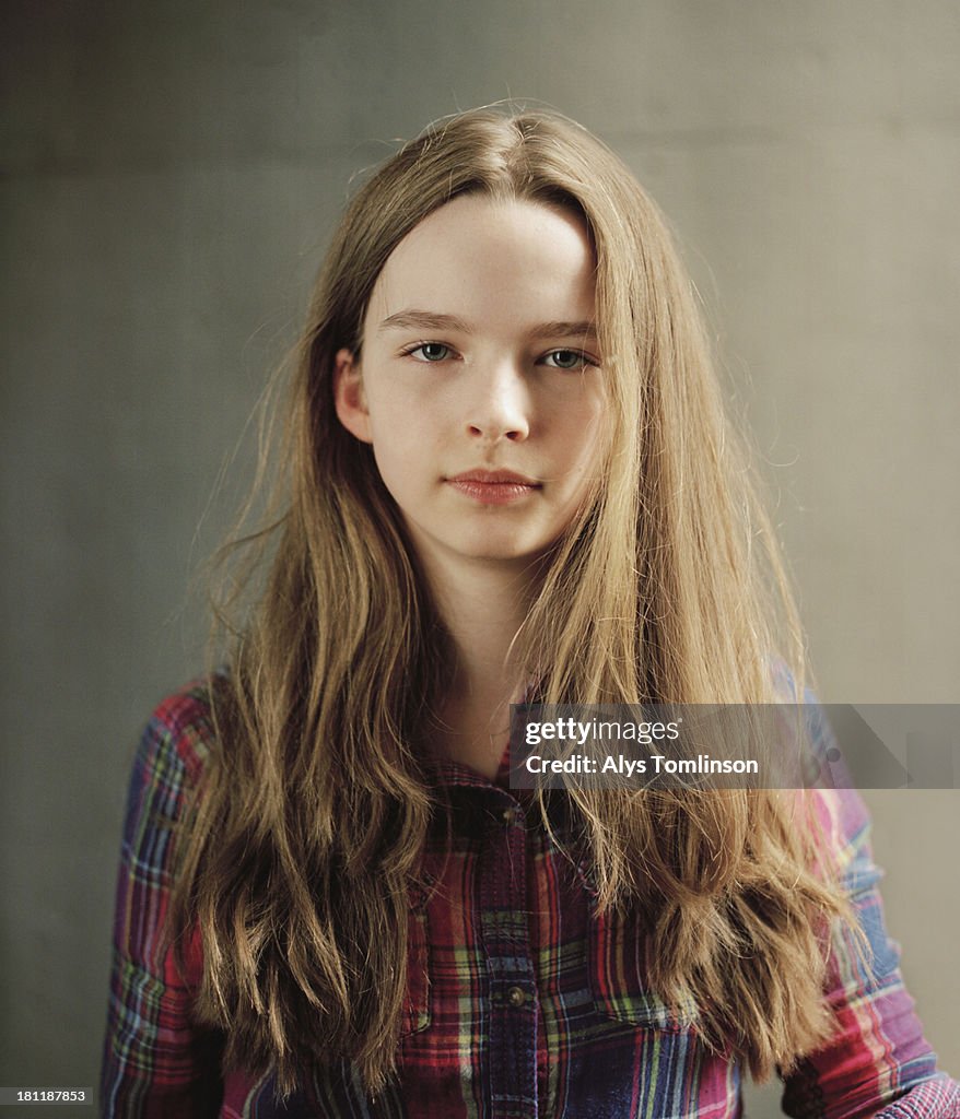 Young girl in front of a wall looking into camera