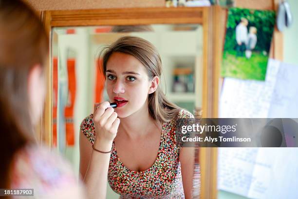 girl looking into a mirror applying lipstick - amenities stock-fotos und bilder