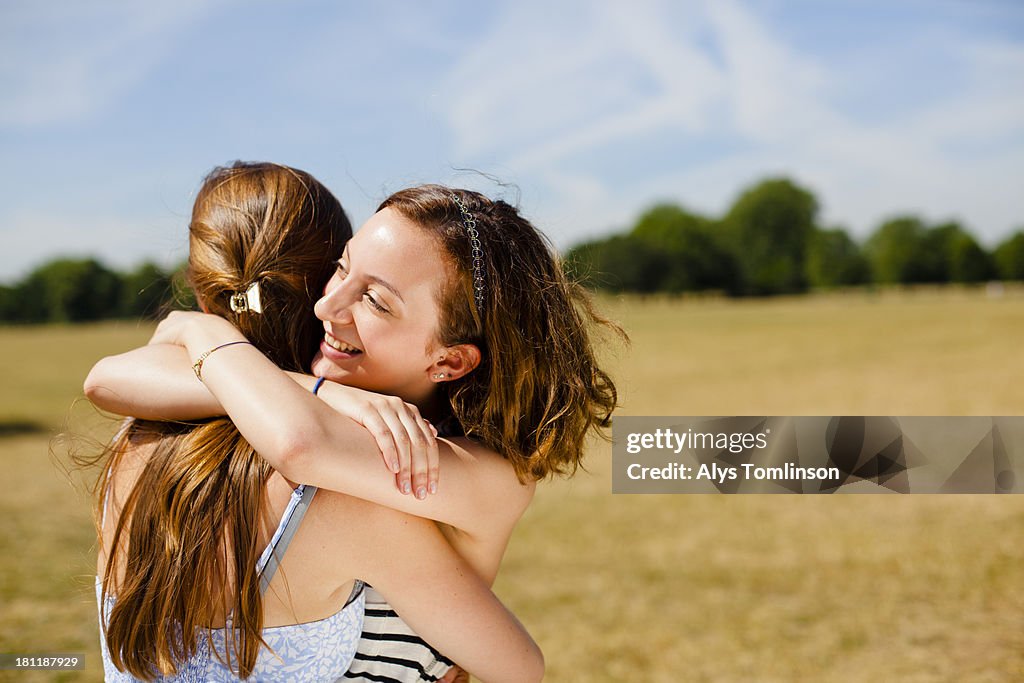 Girls embracing outside in the sun on a common