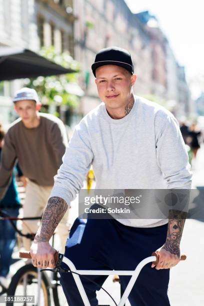 two young men riding bicycles in city area - boy tracksuit stock pictures, royalty-free photos & images