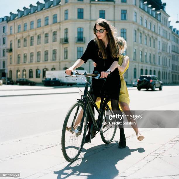 two women on same bike - copenhagen cycling stock pictures, royalty-free photos & images