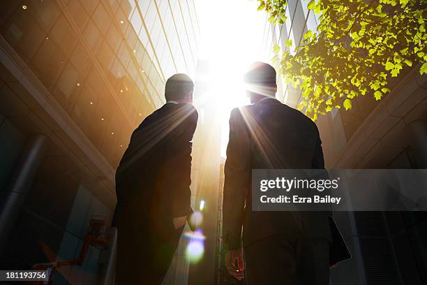 two businessmen looking up into the sun. - business expansion photos et images de collection