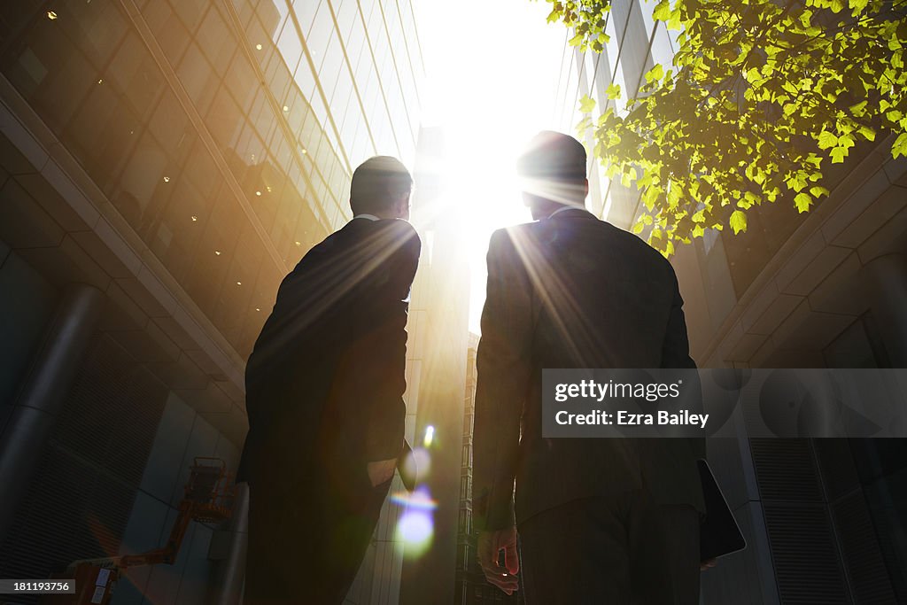 Two businessmen looking up into the sun.