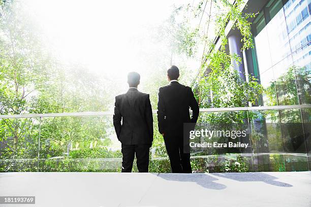 two businessmen surrounded by trees. - green suit stock-fotos und bilder