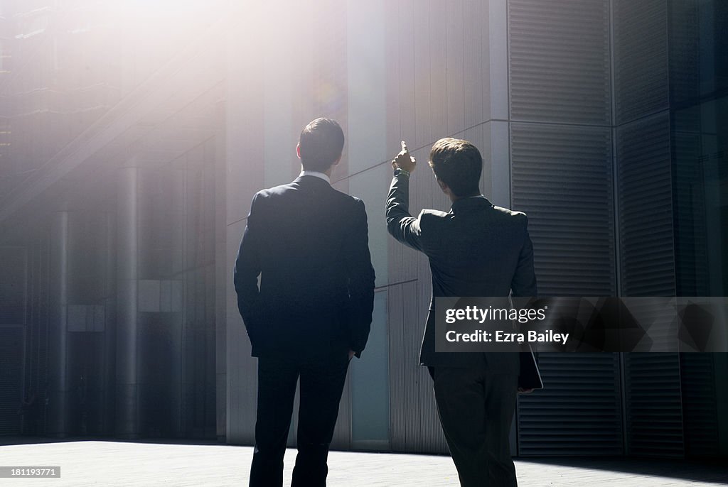 Two businessmen looking up at city skyline.