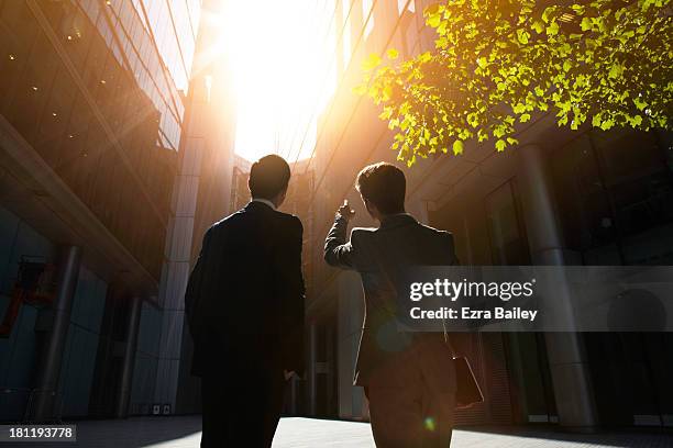 two businessmen looking up into the sun. - backlit stock-fotos und bilder