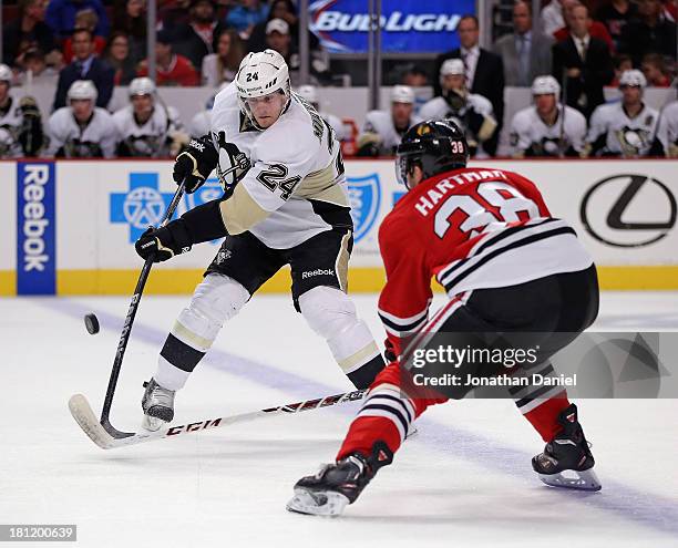 Brendan Mikkelson of the Pittsburgh Penguins tries to shoot under pressure from Ryan Hartman of the Chicago Blackhakws during an exhibition game at...