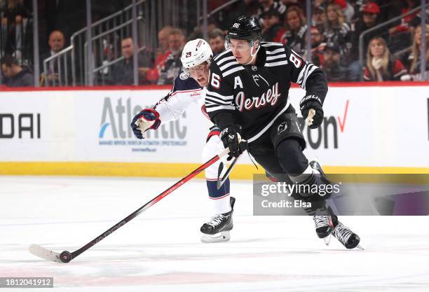 Jack Hughes of the New Jersey Devils takes the puck as Patrik Laine of the Columbus Blue Jackets defends during the second period at Prudential...