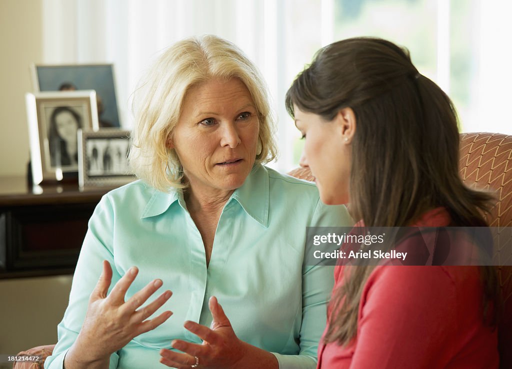 Caucasian mother and daughter talking on sofa