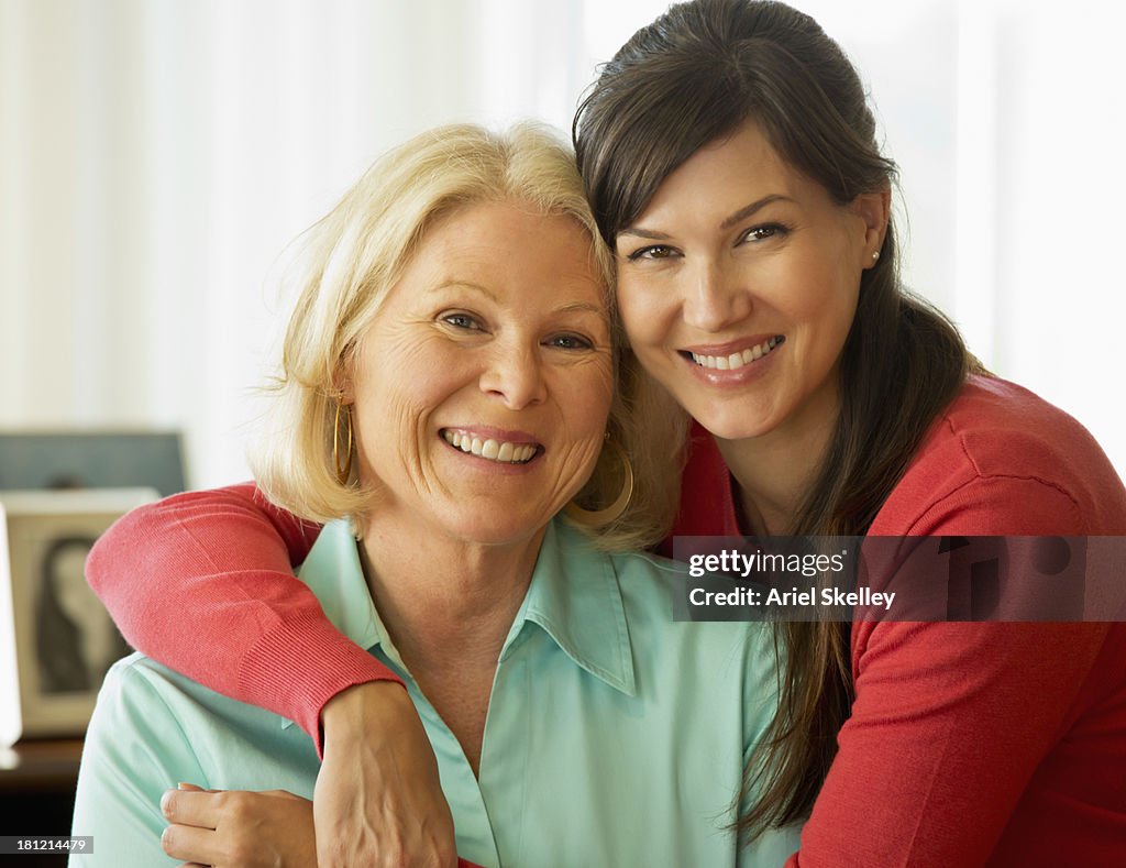 Caucasian mother and daughter hugging on sofa