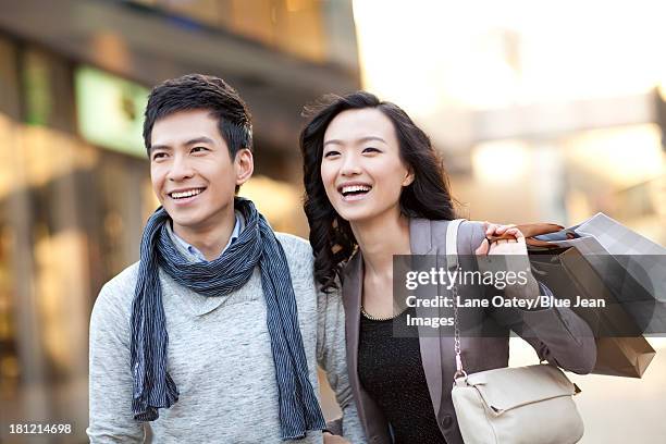 fashionable young couple shopping - a woman carrying a shopping bag walks out of a mall in beijing stock-fotos und bilder