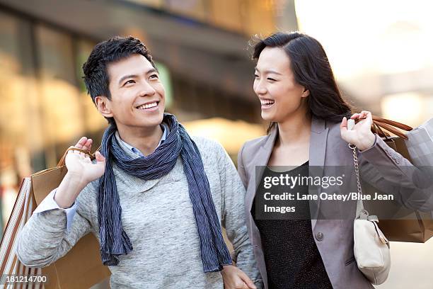 fashionable young couple shopping - a woman carrying a shopping bag walks out of a mall in beijing stock-fotos und bilder