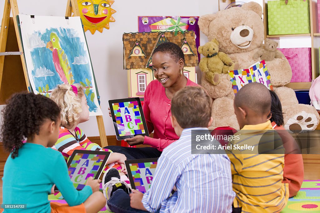 Teacher and children using tablet computers in class