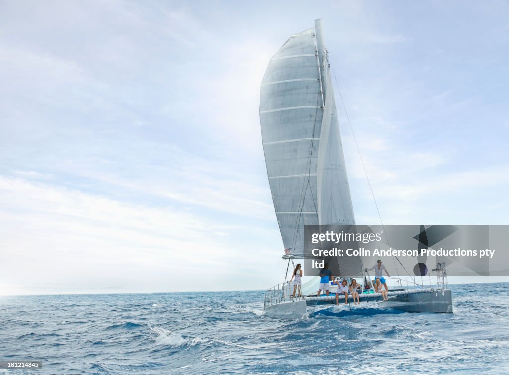 Friends riding sail boat in water