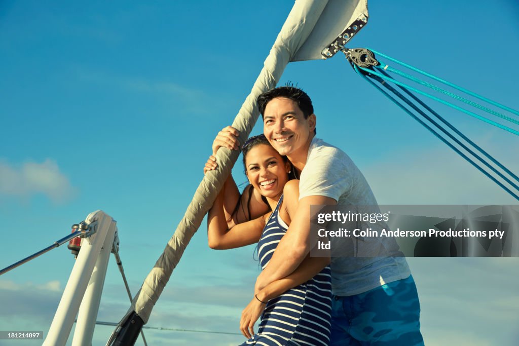 Smiling couple hugging on sailboat