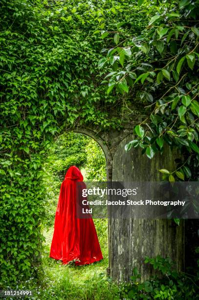 caucasian woman wearing red hooded cloak in garden - formal garden - fotografias e filmes do acervo