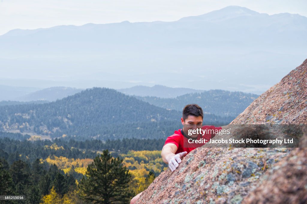 Mixed race climber scaling steep rock face