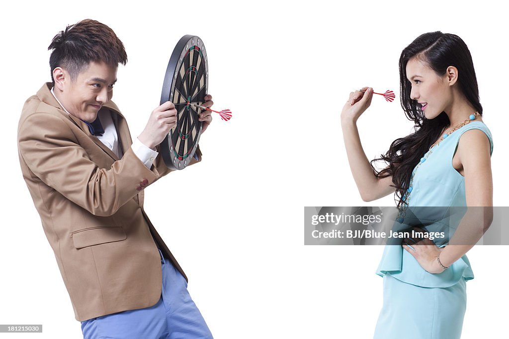 Stylish young people with darts and dartboard