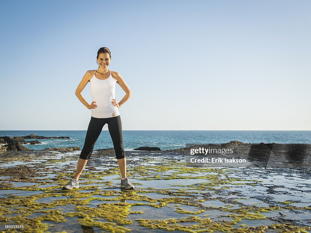 Mixed race runner standing on rocky beach