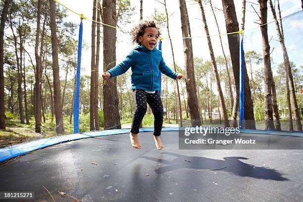 mixed race girl jumping on trampoline - trampoline jump stock-fotos und bilder