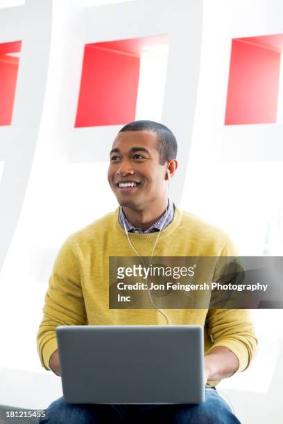 mixed race man using laptop and earphones - black man laptop photos et images de collection