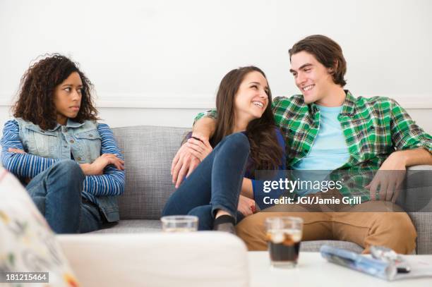 couple ignoring friend on sofa - 3 liga fotografías e imágenes de stock