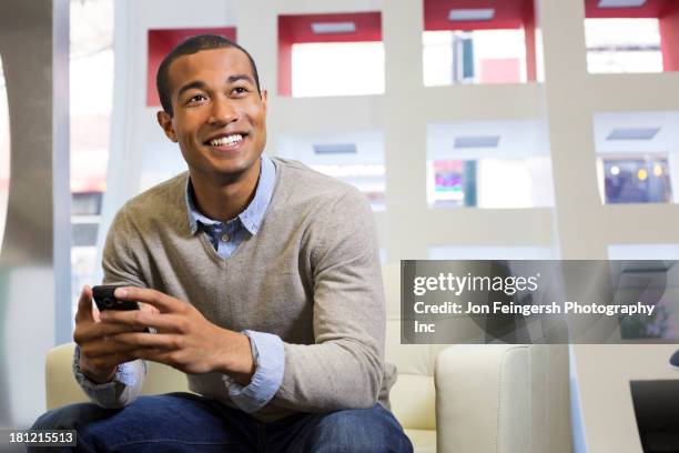 black businessman using cell phone in office - african american business man stock-fotos und bilder