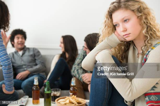 woman sitting apart from friends - exclusion stock-fotos und bilder