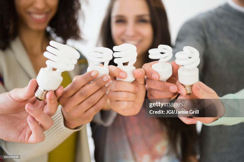 Friends holding fluorescent light bulbs