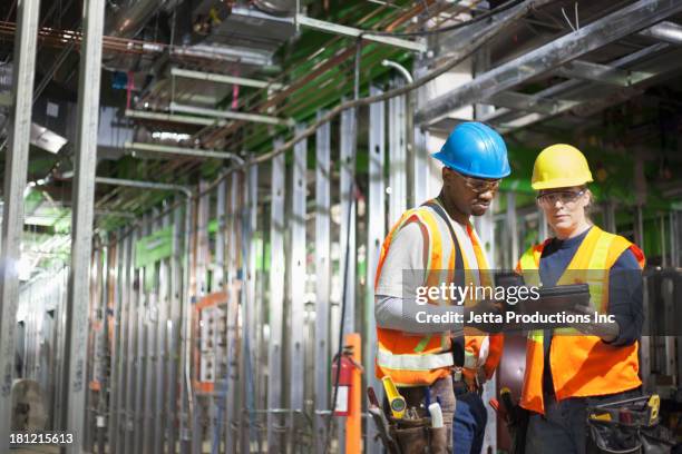 workers using tablet computer on site - construction worker safety equipment stock pictures, royalty-free photos & images