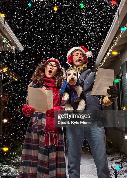 couple singing christmas carols with dog - carol singer stock pictures, royalty-free photos & images