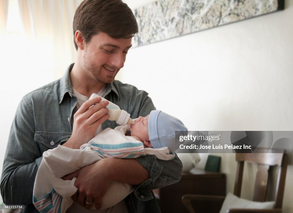 Caucasian father feeding baby bottle