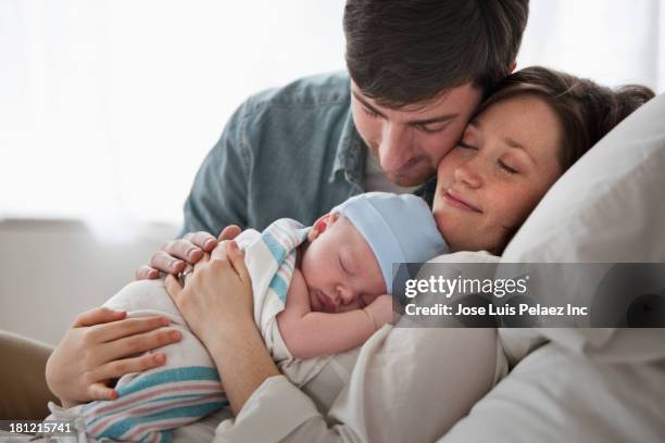 caucasian couple holding baby - father holding sleeping baby stockfoto's en -beelden