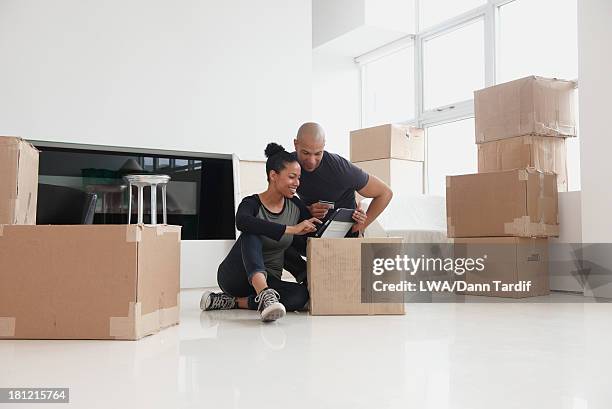 black couple unpacking in new house - house shifting foto e immagini stock