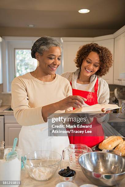 mother and daughter baking in kitchen - baking reading recipe stockfoto's en -beelden
