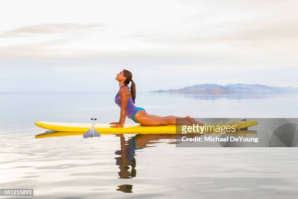 filipino woman practicing yoga on paddle board - practioners enjoy serenity of paddleboard yoga stockfoto's en -beelden