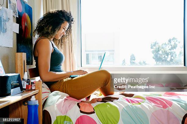 mixed race college student using laptop in dorm - dorm room stock-fotos und bilder
